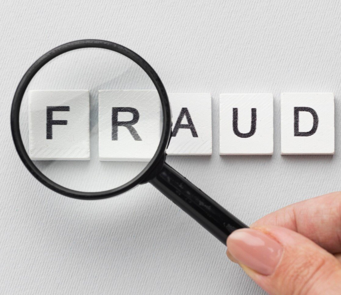 Magnifier enlarging the letters of the word "FRAUD" on a white paper, symbolizing accurate Integrity service.