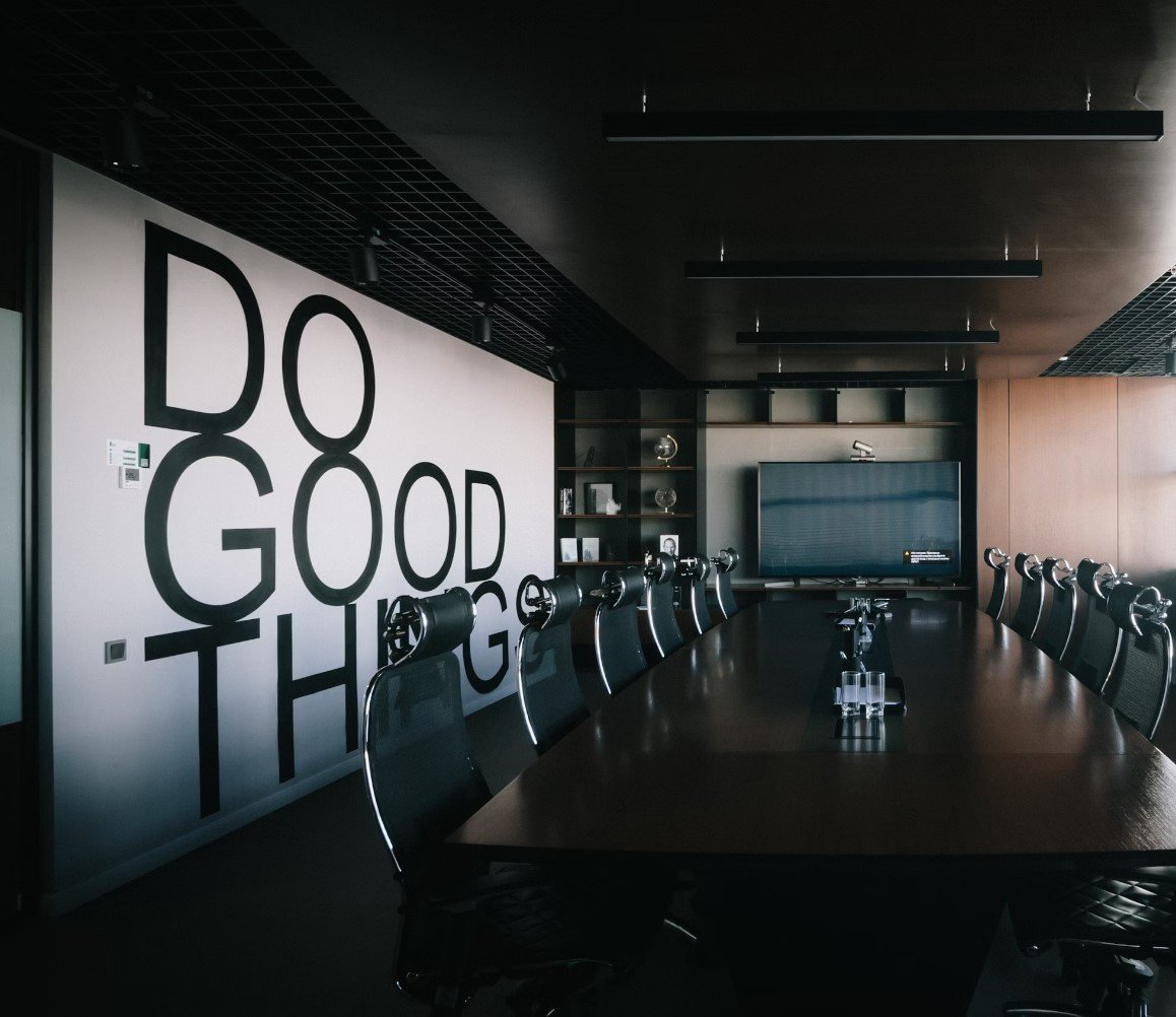 Modern meeting room with a long table, chairs, and a wall displaying the quote "Do Good Thing," symbolizing commitment to effective production optimization.