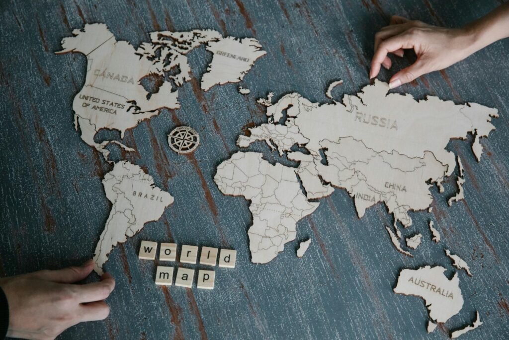 A world map carved on a wooden panel, with two hands composing a puzzle.